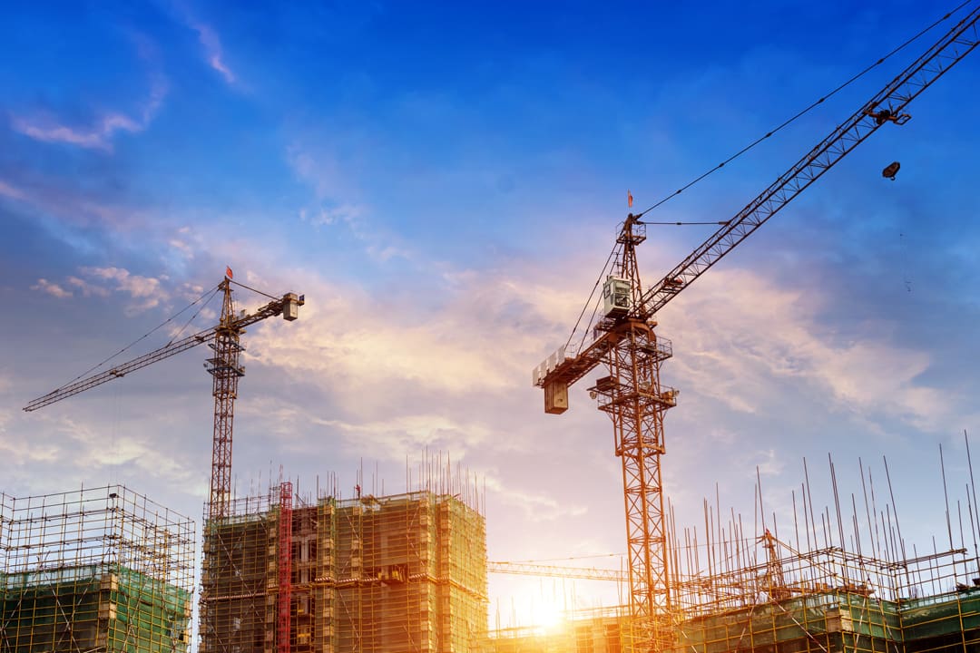 Sunrise behind construction site showing cranes and buildings in progress