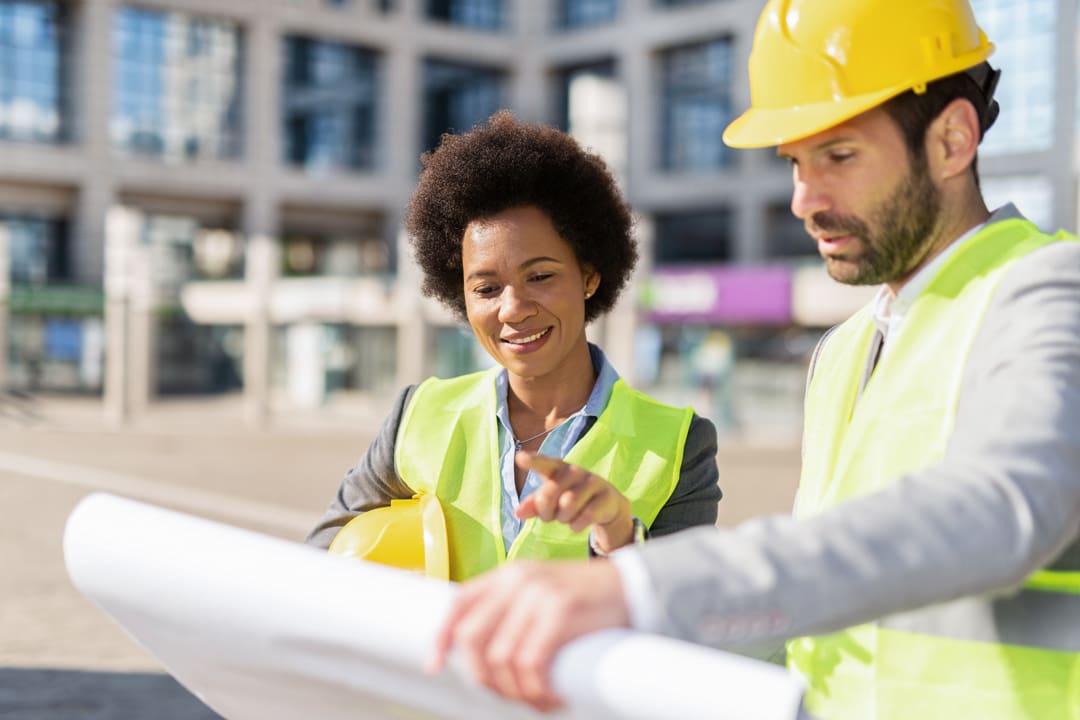 Field Management Software Building contractors analyzing blueprint at construction site